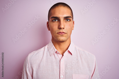 Young handsome man wearing elegant shirt over pink isolated background with a confident expression on smart face thinking serious © Krakenimages.com
