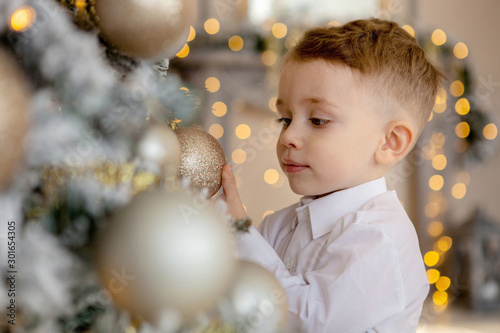 little boy decorates a Christmas tree for Christmas