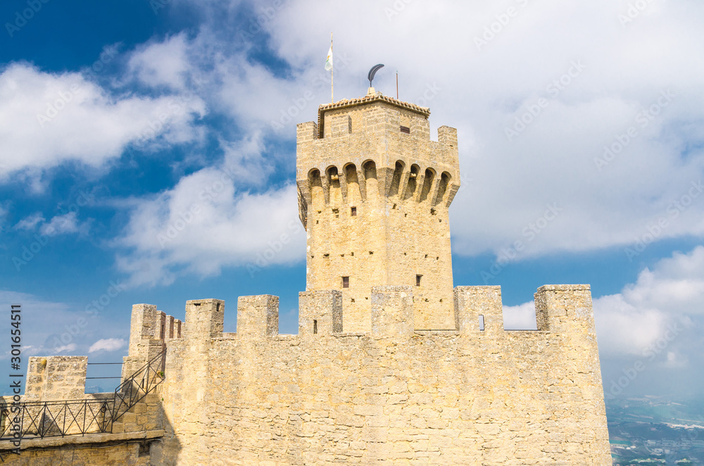 Republic San Marino Seconda Torre La Cesta second fortress tower with merlons and brick walls on Mount Titano stone rock, blue sky white clouds background