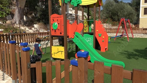 Castellorizo island, Greece - 1st of October 2019: 4K Boy alone plays on the children playground photo