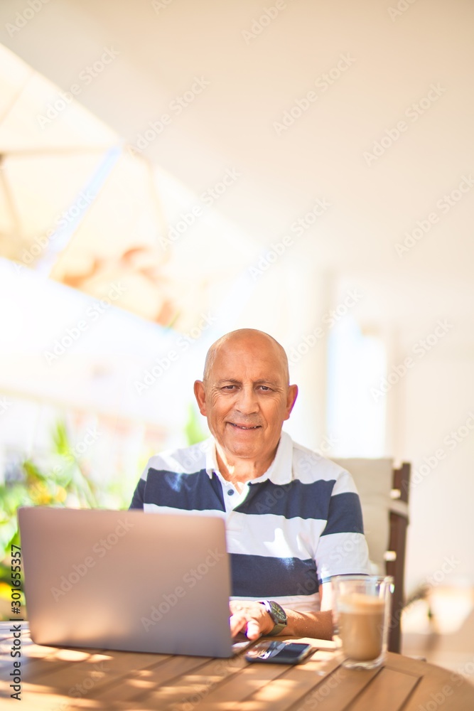 Senior handsome man smiling happy and confident. Sitting using laptop at terrace