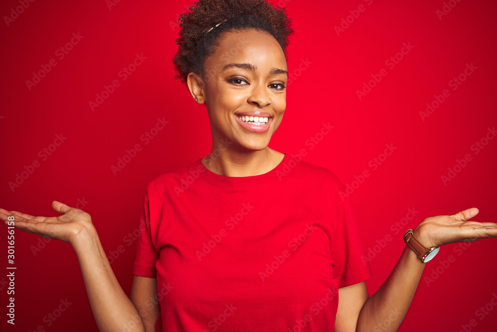 Young beautiful african american woman with afro hair over isolated red background smiling showing both hands open palms, presenting and advertising comparison and balance Young beautiful african american woman with afro hair over isolated red background smiling showing both hands open palms, presenting and advertising comparison and balance