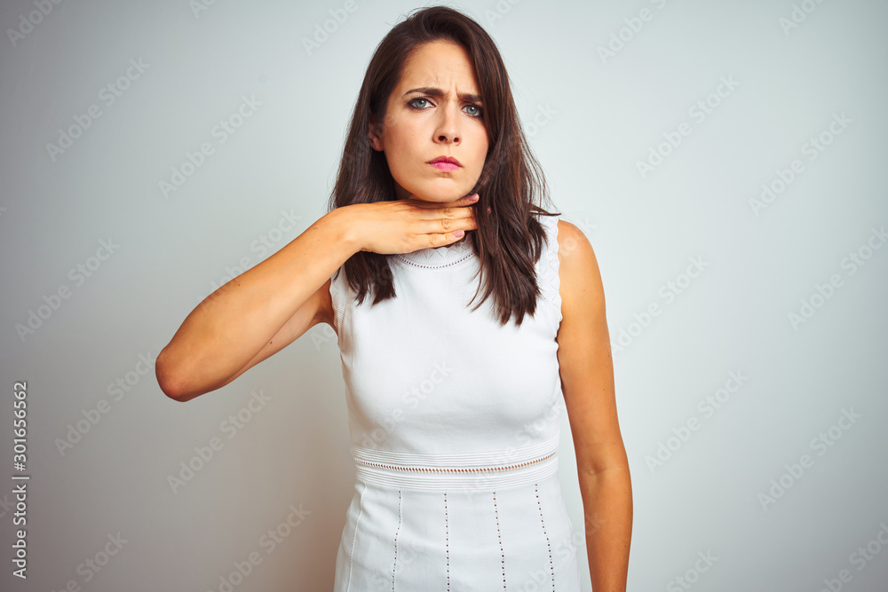 Young beautiful woman wearing dress standing over white isolated background cutting throat with hand as knife, threaten aggression with furious violence Young beautiful woman wearing dress standing over white isolated background cutting throat with hand as knife, threaten aggression with furious violence