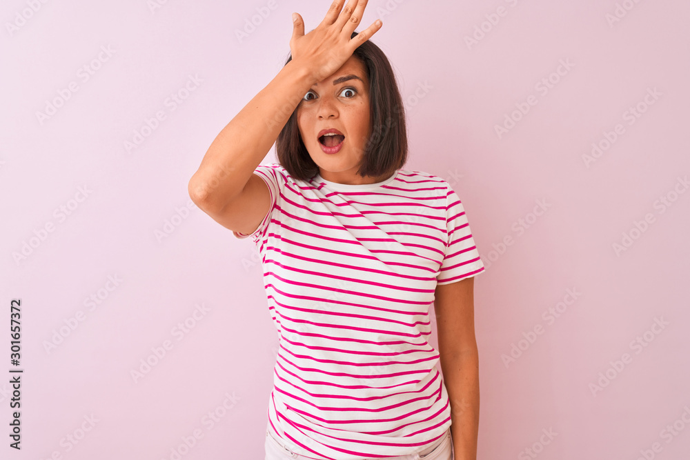 Young beautiful woman wearing striped t-shirt standing over isolated pink background surprised with hand on head for mistake, remember error. Forgot, bad memory concept. Young beautiful woman wearing striped t-shirt standing over isolated pink background surprised with hand on head for mistake, remember error. Forgot, bad memory concept.