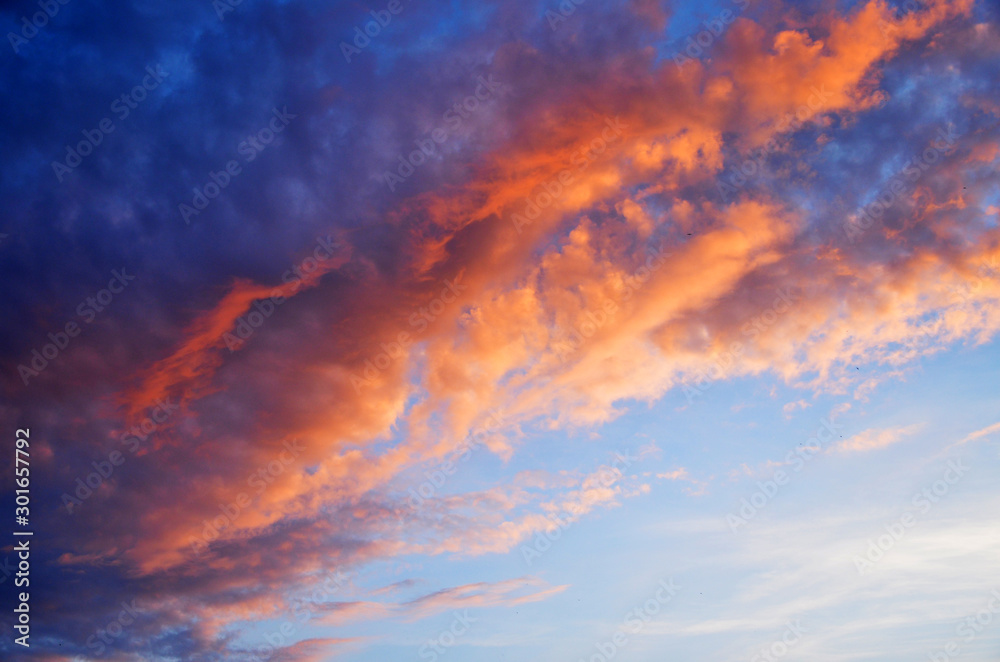 Violet-orange clouds in the sky, illuminated by the rays of the sun in the evening Violet-orange clouds in the sky, illuminated by the rays of the sun in the evening