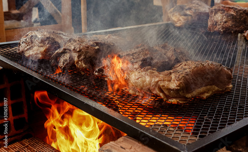 a barbecue grill of bricks on fire with some pieces of meat