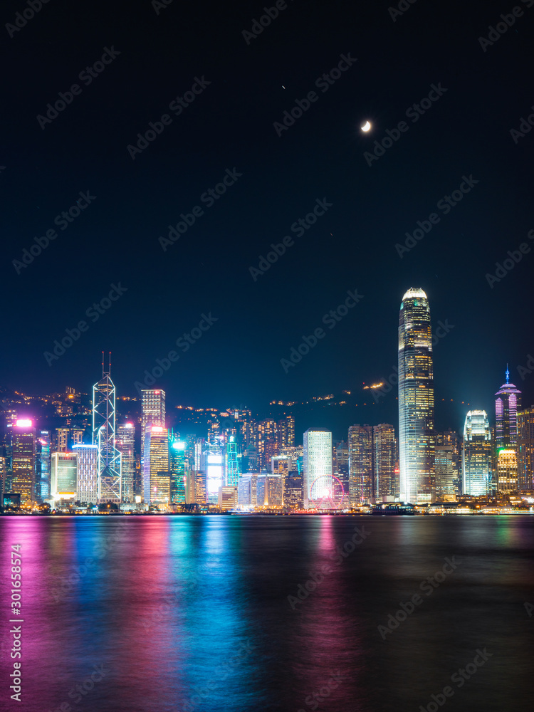Victoria Harbour - Hong Kong skyline at night under the moonlight. Victoria Harbour - Hong Kong skyline at night under the moonlight.