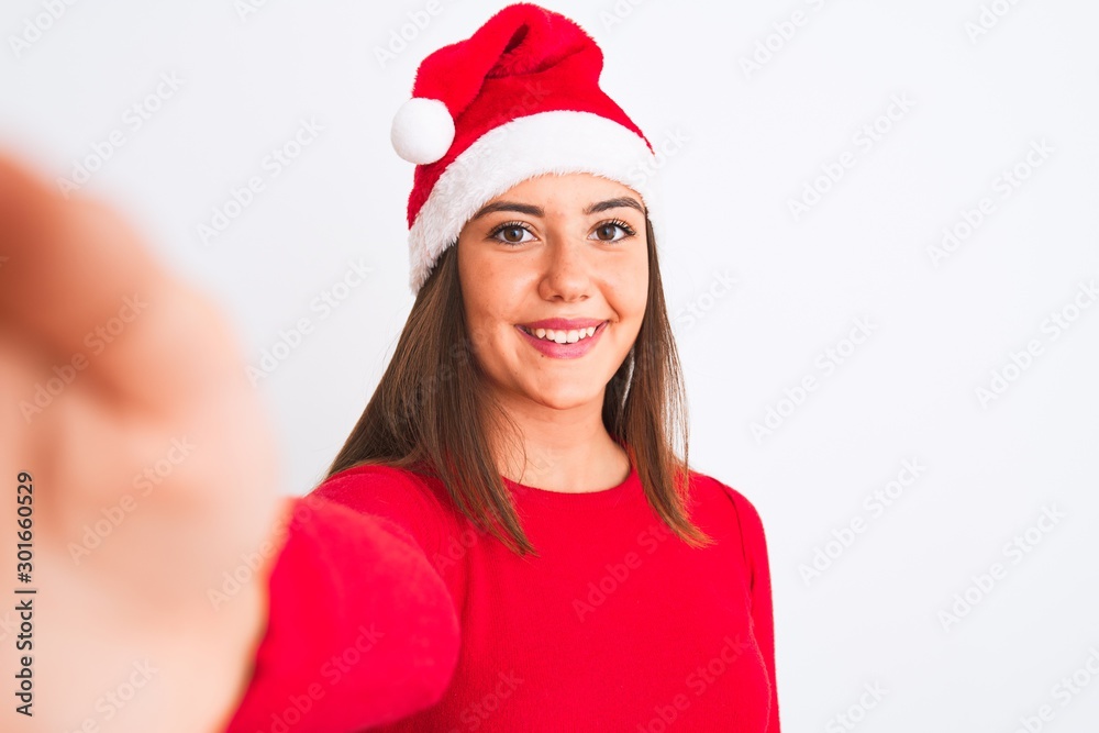 Girl wearing Christmas Santa hat make selfie by camera over isolated white background with a happy face standing and smiling with a confident smile showing teeth Girl wearing Christmas Santa hat make selfie by camera over isolated white background with a happy face standing and smiling with a confident smile showing teeth