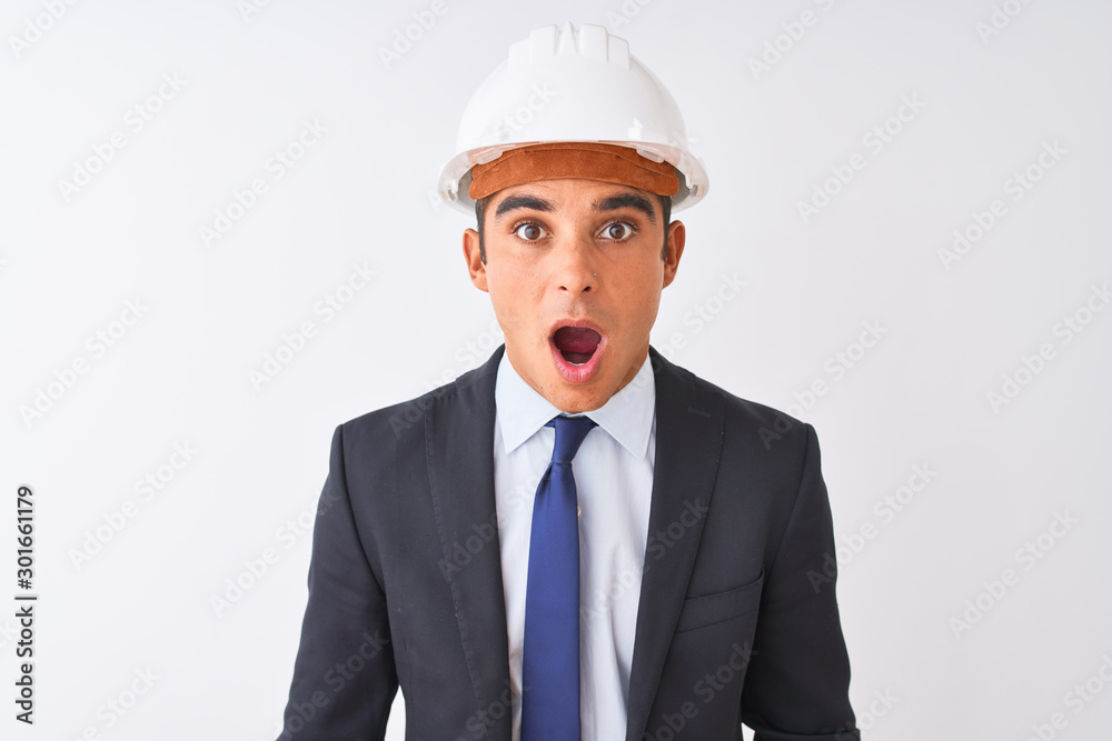 Young handsome architect man wearing suit and helmet over isolated white background afraid and shocked with surprise expression, fear and excited face. Young handsome architect man wearing suit and helmet over isolated white background afraid and shocked with surprise expression, fear and excited face.