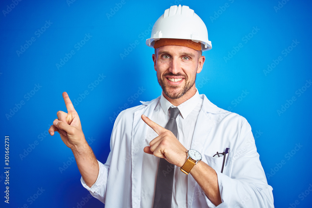 Young handsome engineer man wearing safety helmet over blue isolated background smiling and looking at the camera pointing with two hands and fingers to the side. Young handsome engineer man wearing safety helmet over blue isolated background smiling and looking at the camera pointing with two hands and fingers to the side.