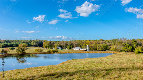 Pond with a farm with a barn and silo in the background