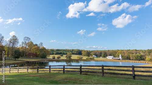 Fence by a pond with a farm with a barn and silo in the background