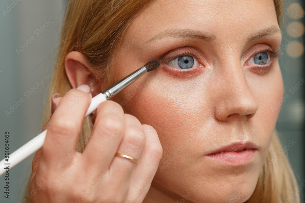 The process of creating makeup. Makeup artist working with a brush on the face of the model. The process of creating makeup. Makeup artist working with a brush on the face of the model.