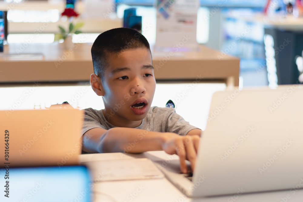 Disabled child on wheelchair trying to use a computer with excitement in an IT shop , Special children's lifestyle, Life in the education age of special need kids, Happy disability kid concept. Disabled child on wheelchair trying to use a computer with excitement in an IT shop , Special children's lifestyle, Life in the education age of special need kids, Happy disability kid concept.