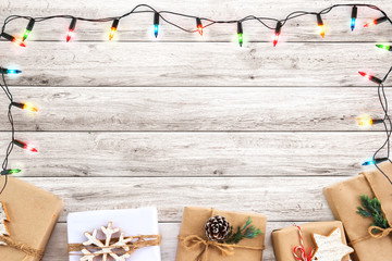 Christmas gift box and lights bulb decoration on white wood plank, frame border design. Merry Christmas and New Year holiday background. top view.