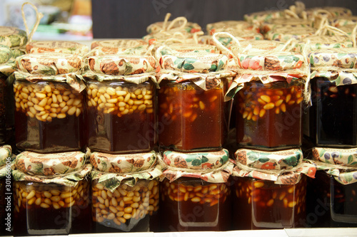  nuts filled with honey in glass jars are on wooden shelves at the food exhibition. Healthy food