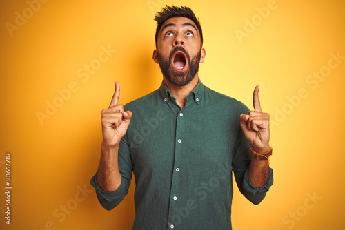 Φωτογραφία Young indian businessman wearing elegant shirt standing over isolated white background amazed and surprised looking up and pointing with fingers and raised arms