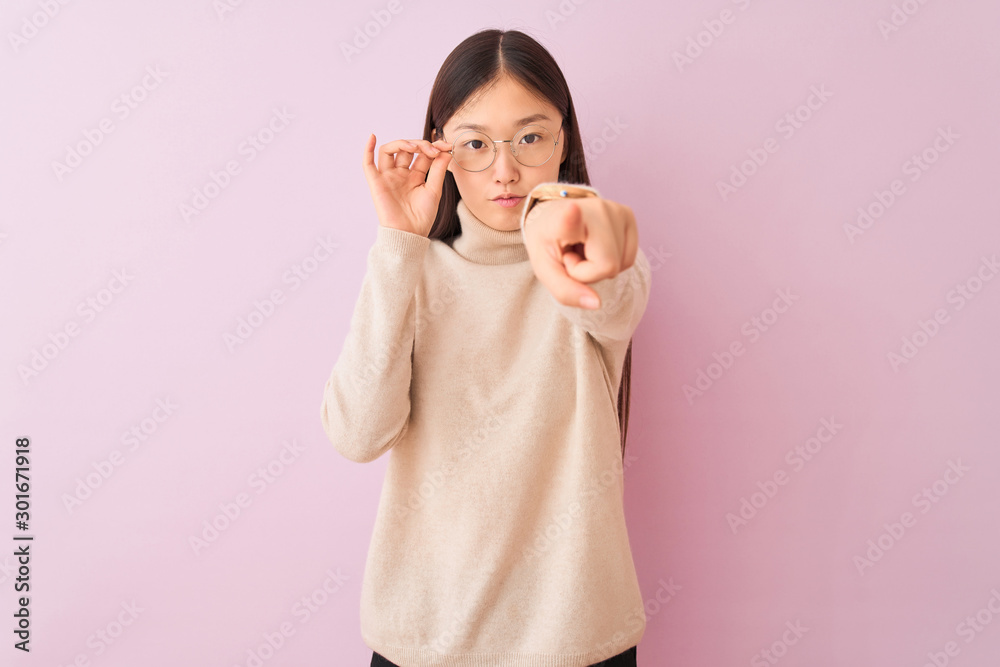 Young chinese woman wearing turtleneck sweater and glasses over isolated pink background pointing with finger to the camera and to you, hand sign, positive and confident gesture from the front Young chinese woman wearing turtleneck sweater and glasses over isolated pink background pointing with finger to the camera and to you, hand sign, positive and confident gesture from the front