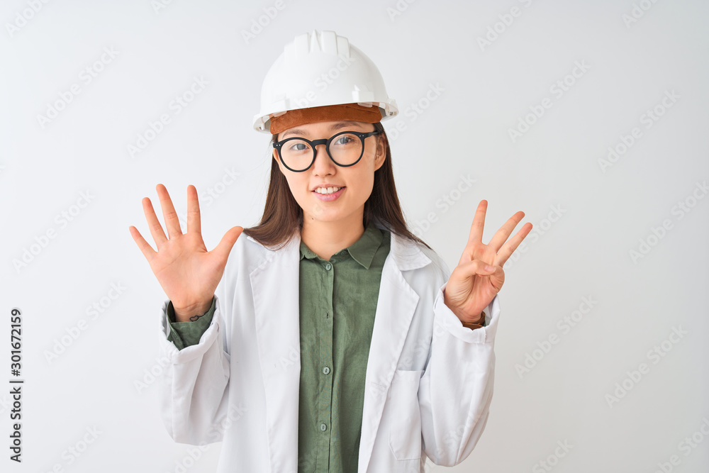 Young chinese engineer woman wearing coat helmet glasses over isolated white background showing and pointing up with fingers number eight while smiling confident and happy. Young chinese engineer woman wearing coat helmet glasses over isolated white background showing and pointing up with fingers number eight while smiling confident and happy.