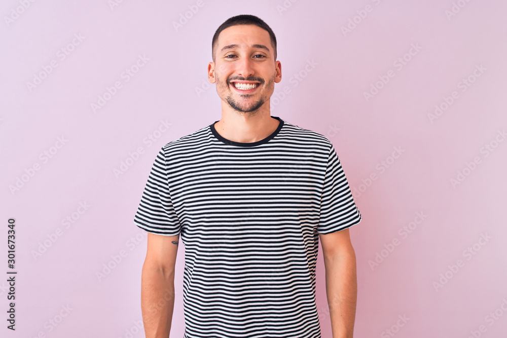 Young handsome man wearing striped t-shirt standing over pink isolated background with a happy and cool smile on face. Lucky person. Young handsome man wearing striped t-shirt standing over pink isolated background with a happy and cool smile on face. Lucky person.