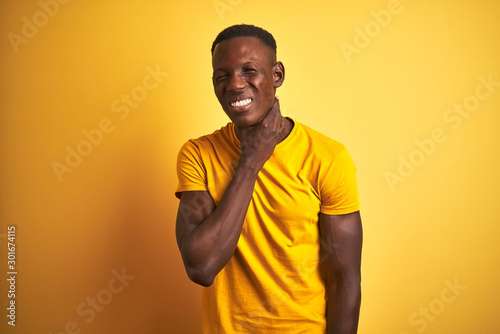 Young african american man wearing casual t-shirt standing over isolated yellow background Touching painful neck, sore throat for flu, clod and infection