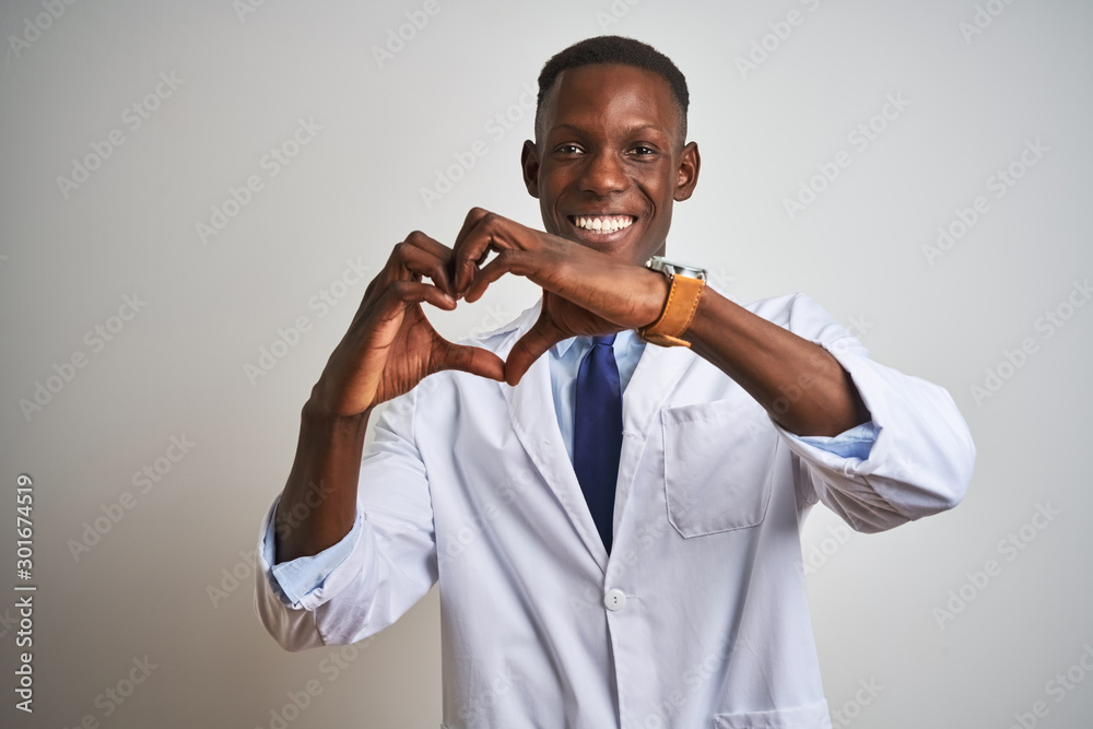Young african american doctor man wearing coat standing over isolated white background smiling in love doing heart symbol shape with hands. Romantic concept. Young african american doctor man wearing coat standing over isolated white background smiling in love doing heart symbol shape with hands. Romantic concept.