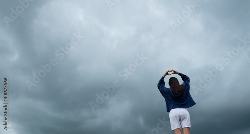 Young woman wearing loose long-sleeved sweater over stormy cloudscape, Beauty and youth