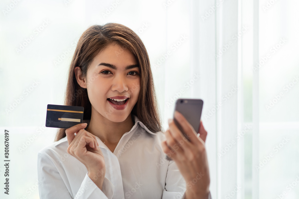 Young Asian woman holding credit card and thinking of online shopping in internet Young Asian woman holding credit card and thinking of online shopping in internet