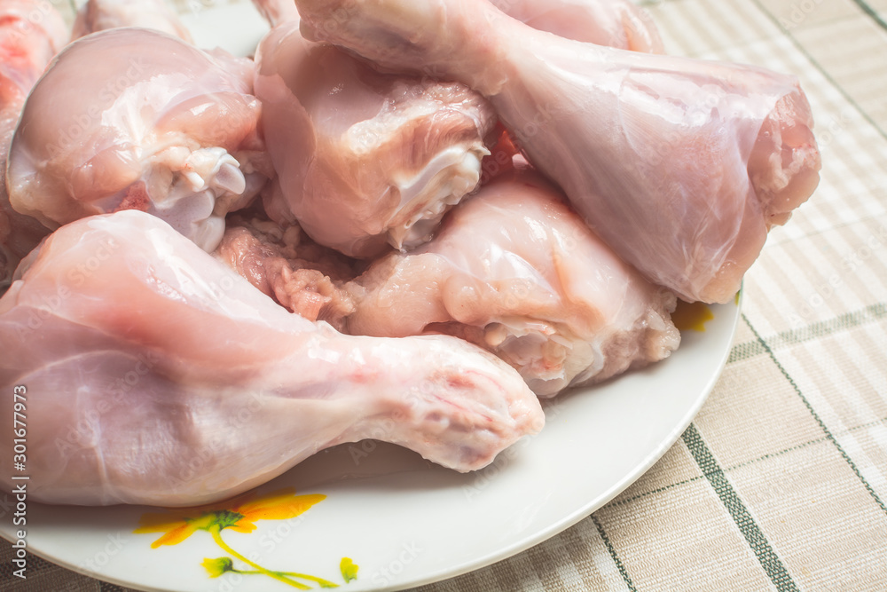 Raw chicken legs on a large plate drain from the water after washing. Raw chicken legs on a large plate drain from the water after washing.