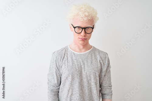 Young albino blond man wearing striped t-shirt and glasses over isolated white background depressed and worry for distress, crying angry and afraid. Sad expression.