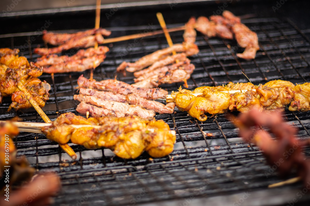 Meat pork chicken beef skewers grilling over charcoal grill  , thailand street food.