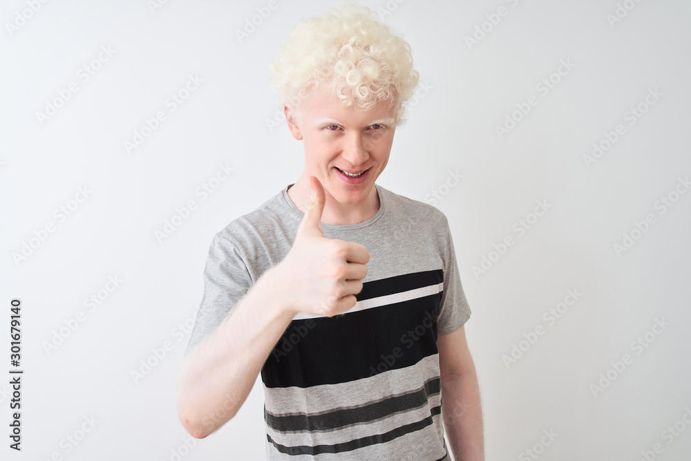 Young albino blond man wearing casual t-shirt standing over isolated white background doing happy thumbs up gesture with hand. Approving expression looking at the camera with showing success. Young albino blond man wearing casual t-shirt standing over isolated white background doing happy thumbs up gesture with hand. Approving expression looking at the camera with showing success.