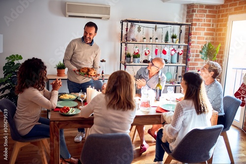 Family and friends dining at home celebrating christmas eve with traditional food and decoration, showing proud turkey cooking