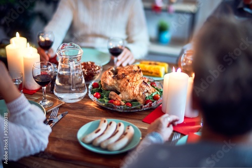 Family and friends dining at home celebrating christmas eve with traditional food and decoration  all sitting on the table together