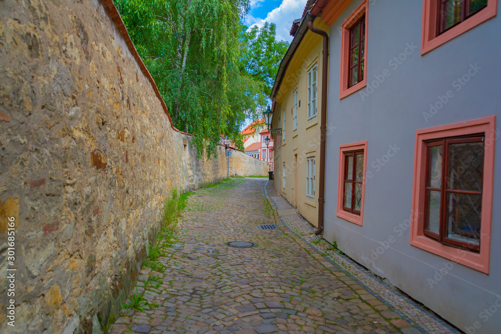 Narrow, empty, cozy street of an old European city with houses and a wall