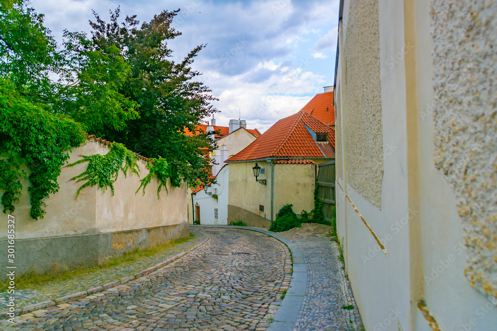 Narrow, empty, cozy street of an old European city with houses and a wall