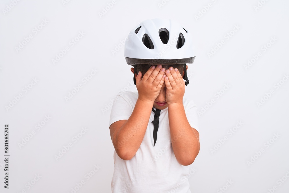 Beautiful kid boy wearing bike security helmet standing over isolated white background suffering from headache desperate and stressed because pain and migraine. Hands on head. Beautiful kid boy wearing bike security helmet standing over isolated white background suffering from headache desperate and stressed because pain and migraine. Hands on head.