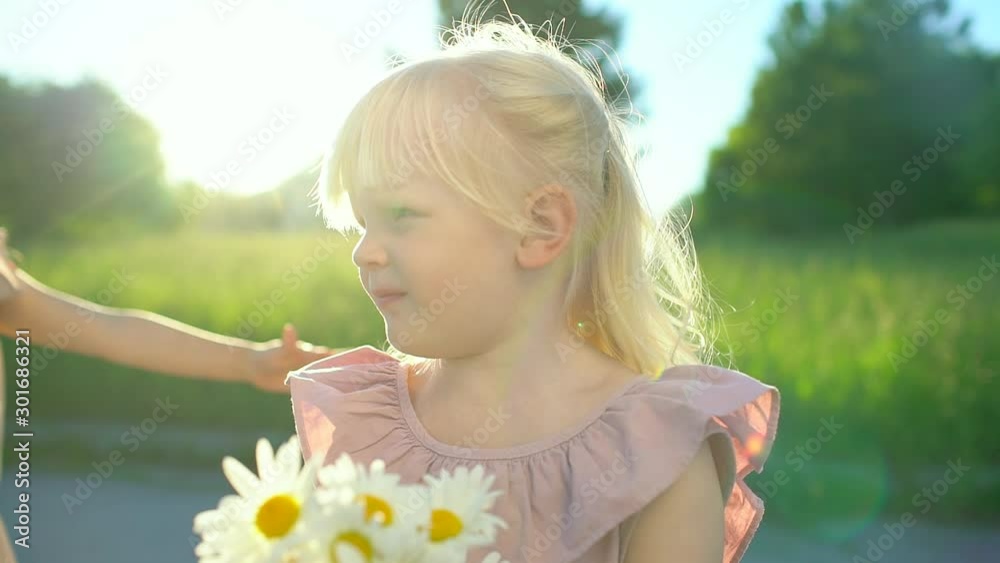 Portrait of adorable little girls sisters friends with bouquet chamomile hugging in field at summer outdoors. Smiling cute child holding flowers looking in camera, childhood, happiness, happy family Portrait of adorable little girls sisters friends with bouquet chamomile hugging in field at summer outdoors. Smiling cute child holding flowers looking in camera, childhood, happiness, happy family