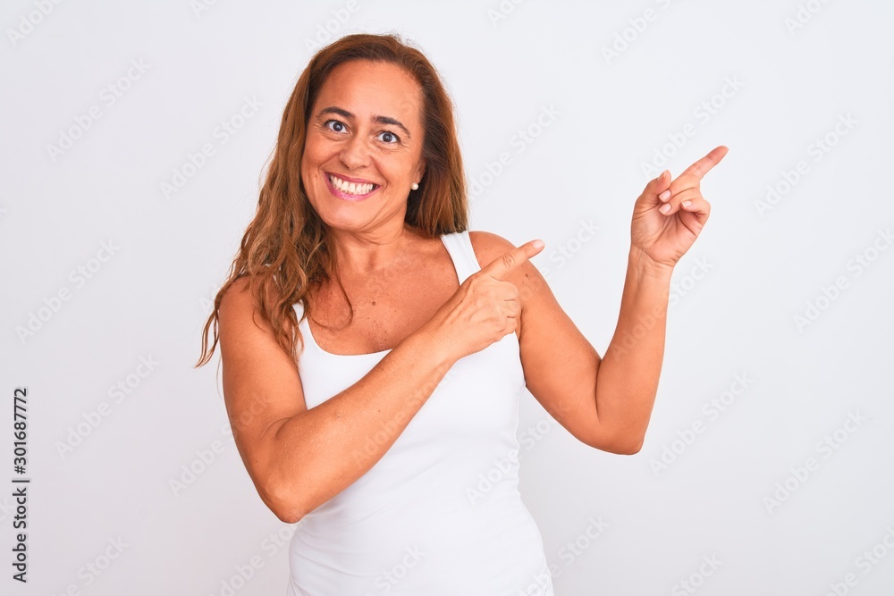 Middle age mature woman standing over white isolated background smiling and looking at the camera pointing with two hands and fingers to the side. Middle age mature woman standing over white isolated background smiling and looking at the camera pointing with two hands and fingers to the side.