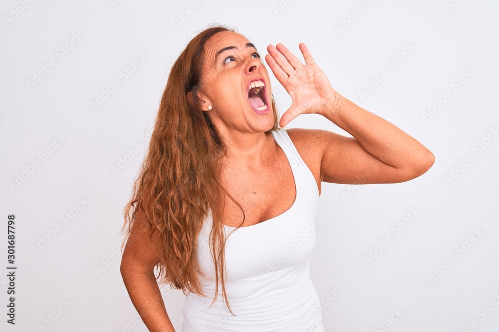 Middle age mature woman standing over white isolated background shouting and screaming loud to side with hand on mouth. Communication concept. Middle age mature woman standing over white isolated background shouting and screaming loud to side with hand on mouth. Communication concept.