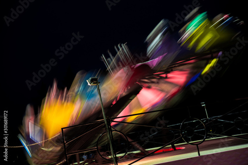 Amusement park ride fast spinning carousel roundabout with motion blur. Fun fair carnival rides at fairground. Family vacation, leisure and recreation concept