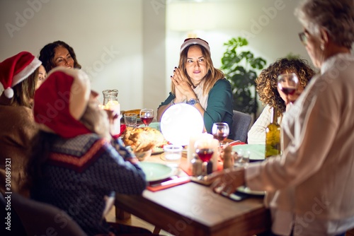 Beautiful group of women smiling happy and confident. On of them holding cup of wine speaking speech celebrating christmas at home