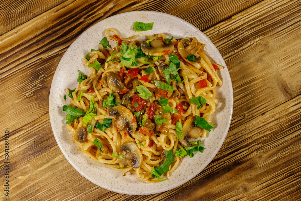 Pasta with mushrooms and tomato sauce on wooden table. Top view Pasta with mushrooms and tomato sauce on wooden table. Top view