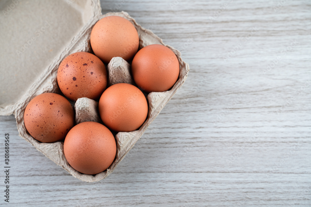 Closeup of raw chicken eggs in egg box on brown wooden background, organic food from nature good for health Closeup of raw chicken eggs in egg box on brown wooden background, organic food from nature good for health