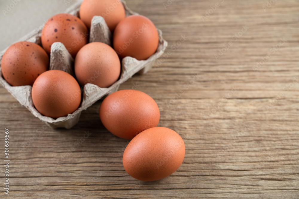 Closeup of raw chicken eggs in egg box on brown wooden background, organic food from nature good for health Closeup of raw chicken eggs in egg box on brown wooden background, organic food from nature good for health