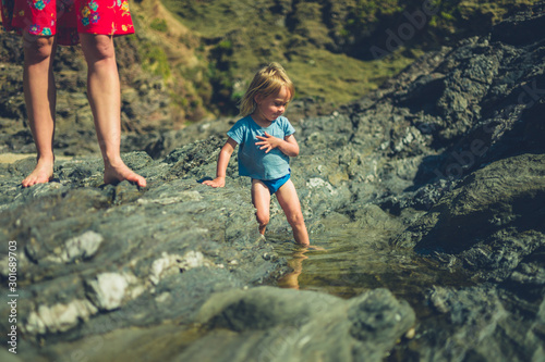 Little toddler playing in rockpools with his mother © LoloStock