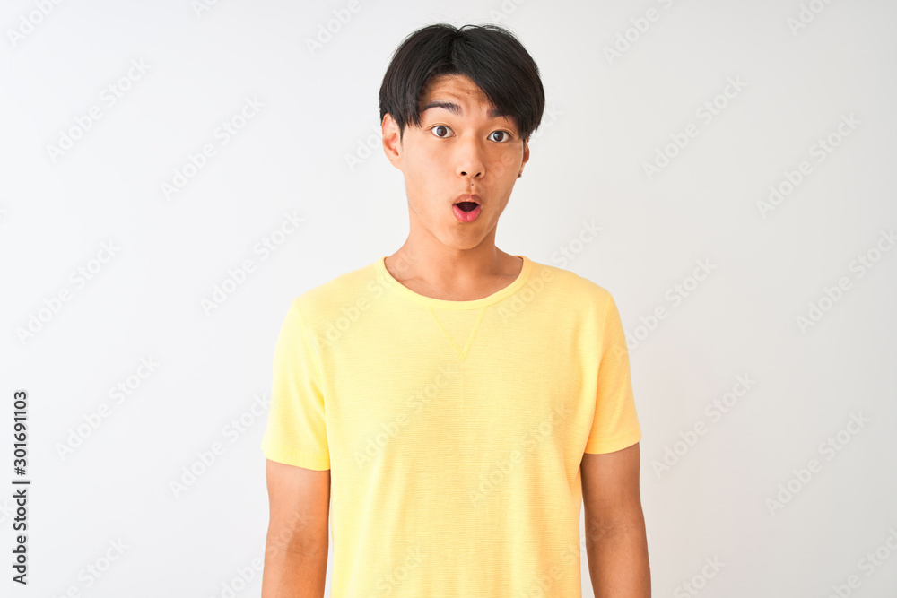 Chinese man wearing yellow casual t-shirt standing over isolated white background afraid and shocked with surprise expression, fear and excited face. Chinese man wearing yellow casual t-shirt standing over isolated white background afraid and shocked with surprise expression, fear and excited face.