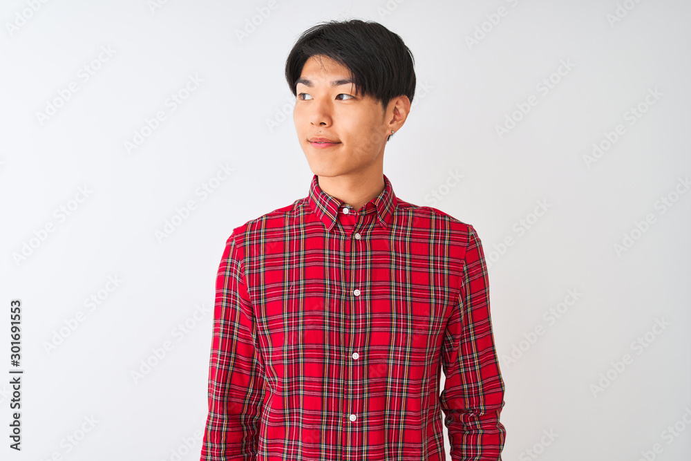 Young chinese man wearing casual red shirt standing over isolated white background smiling looking to the side and staring away thinking. Young chinese man wearing casual red shirt standing over isolated white background smiling looking to the side and staring away thinking.