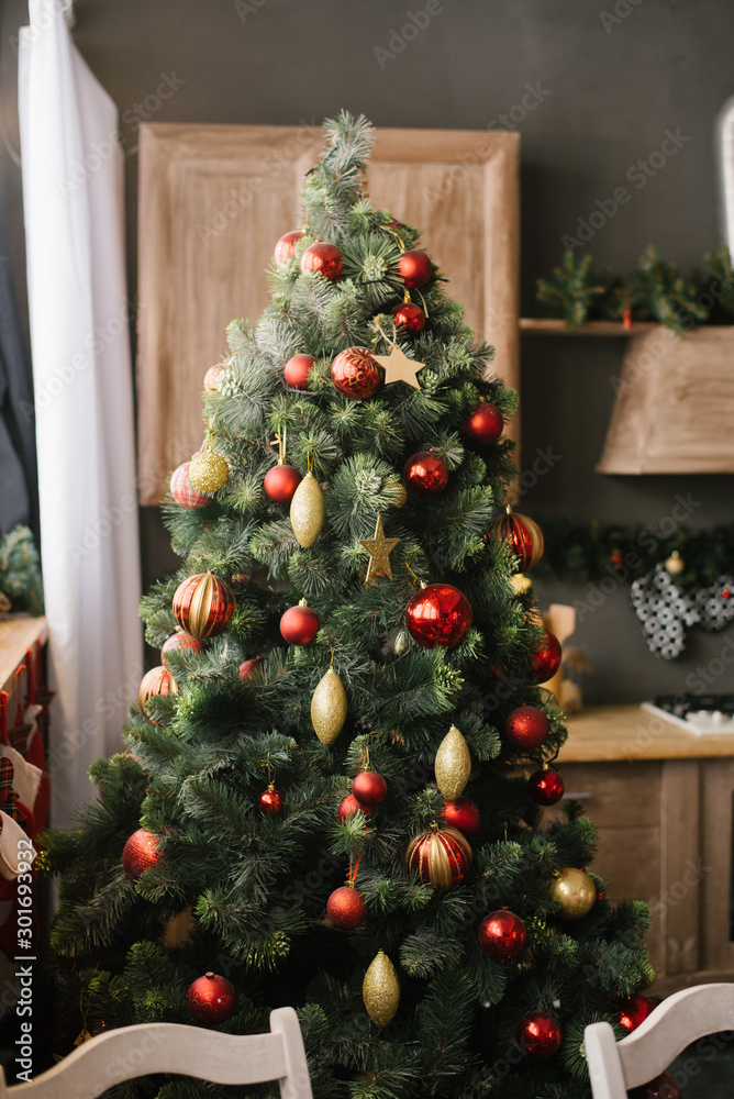 Christmas tree with red and gold toys on it in the dining room of the house