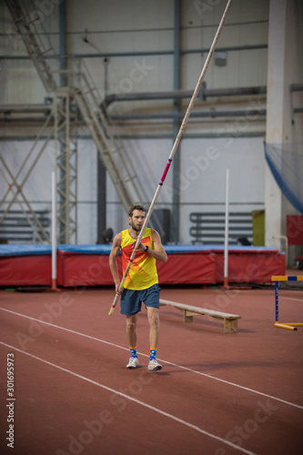 Pole vaulting indoors - a man standing on the track with a pole © KONSTANTIN SHISHKIN